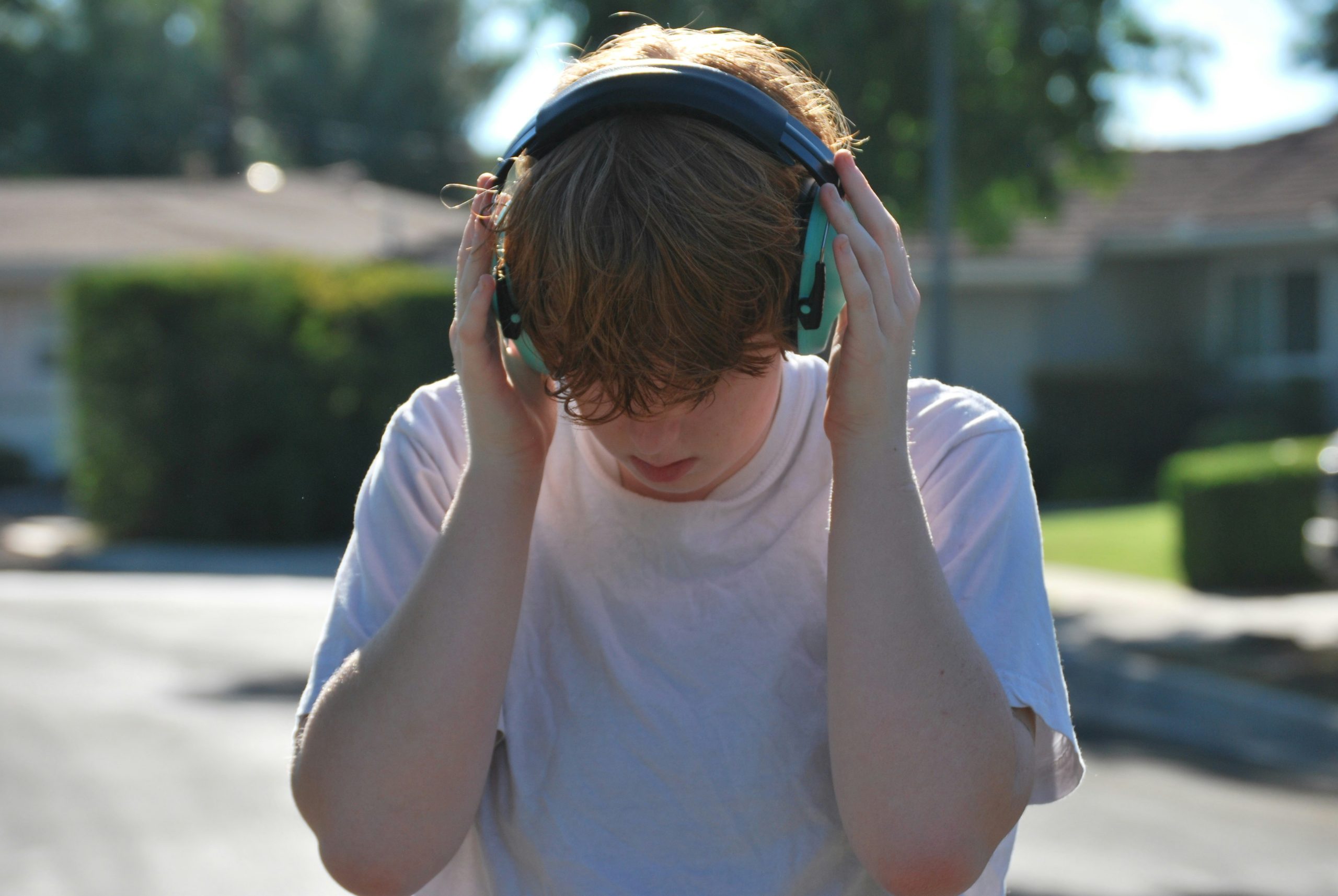 Autistic adult using noise-cancelling headphones in a workplace for sensory comfort.